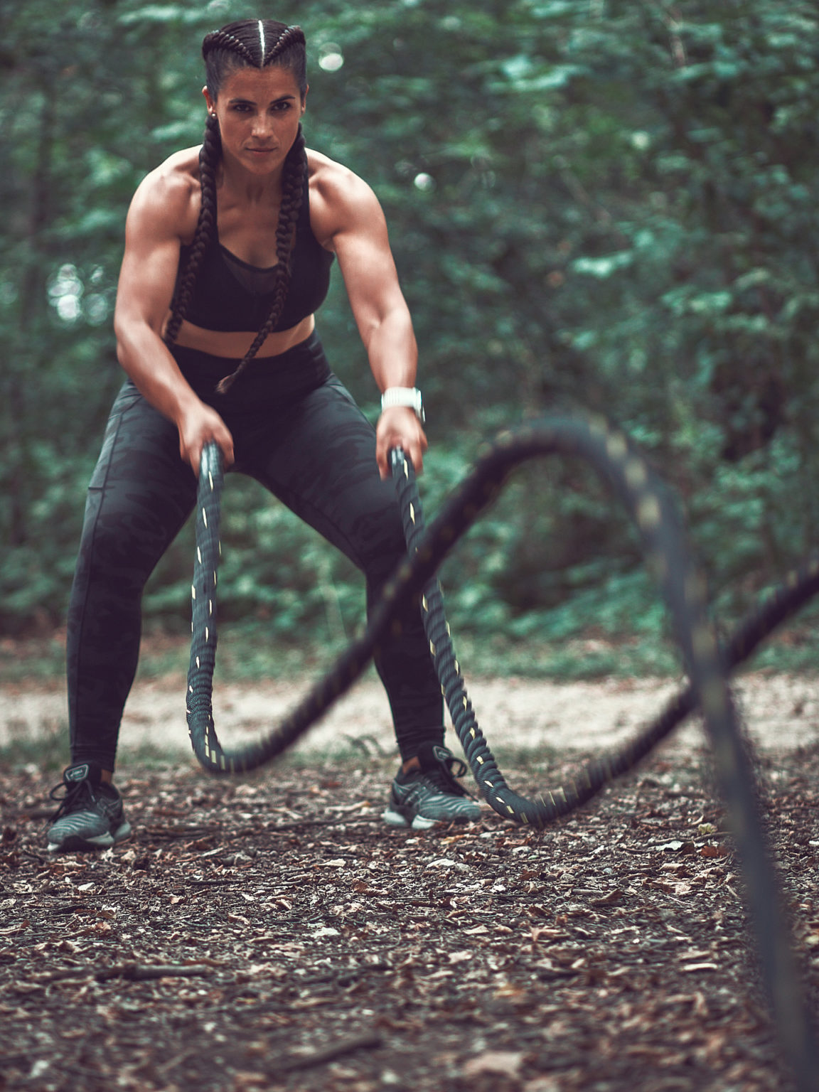 Portrait d'une coach sportive prise en extérieur en faisant un exercice de corde