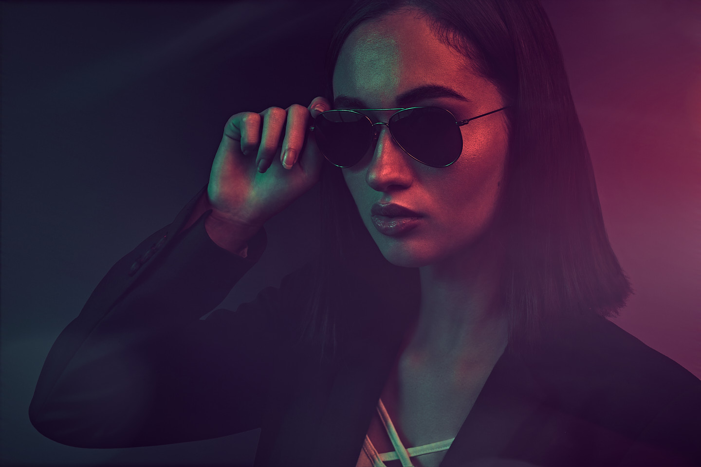 Portrait fashion d'un model avec lunette sur un fond sombre et coloré