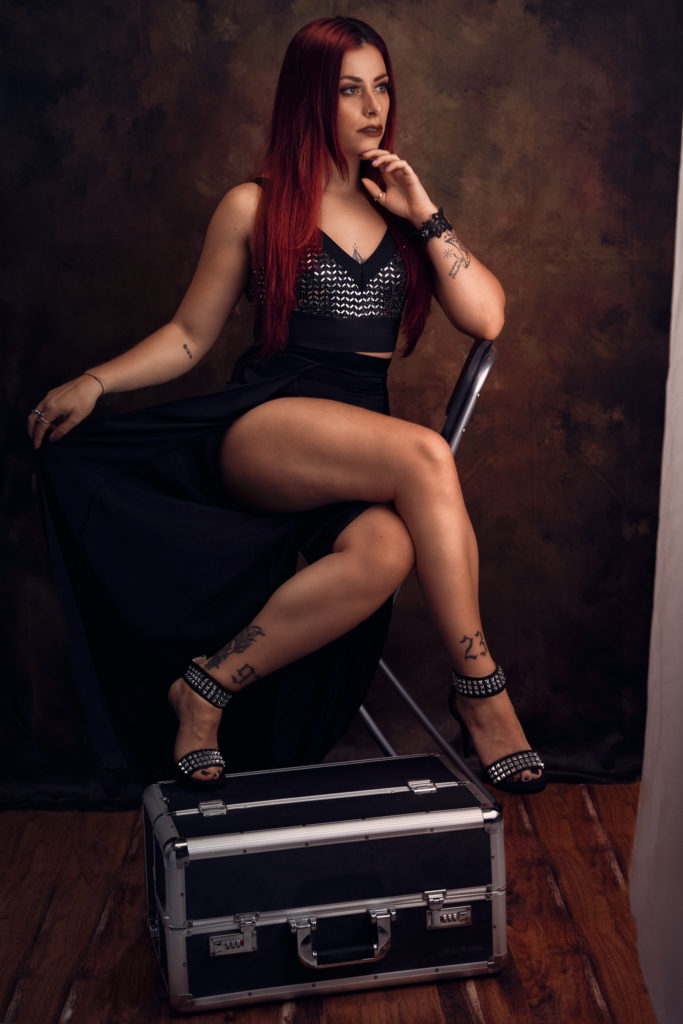 Femme aux cheveux rouges et aux belles jambes assises habits en noir