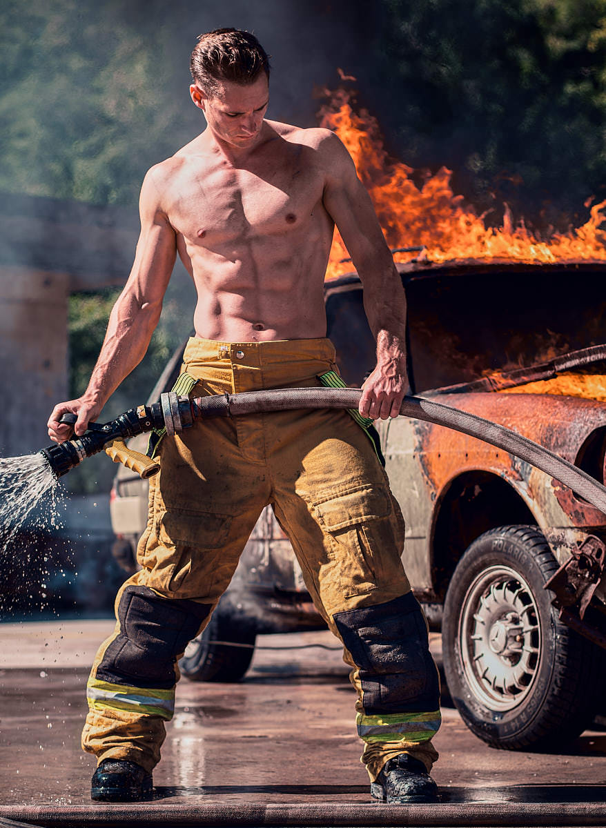 Homme pompier devant voiture en flamme