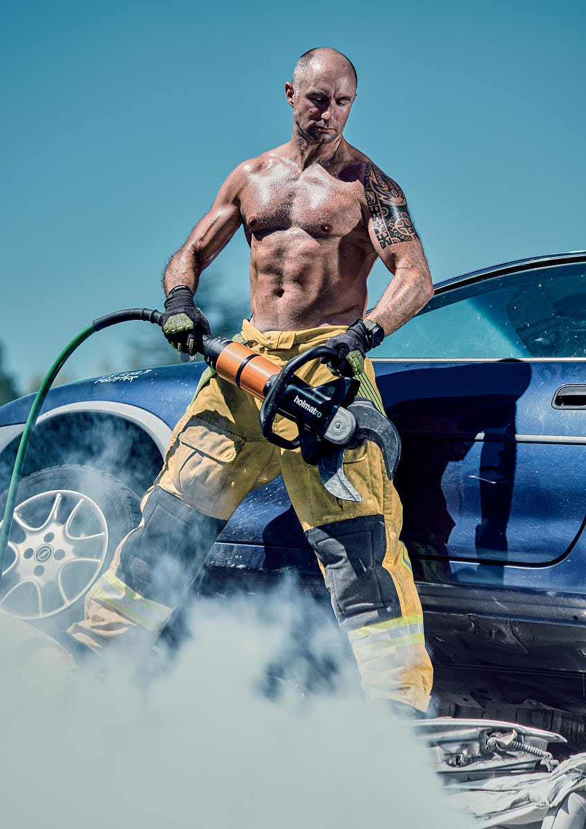 Homme pompier devant carcasse de voiture