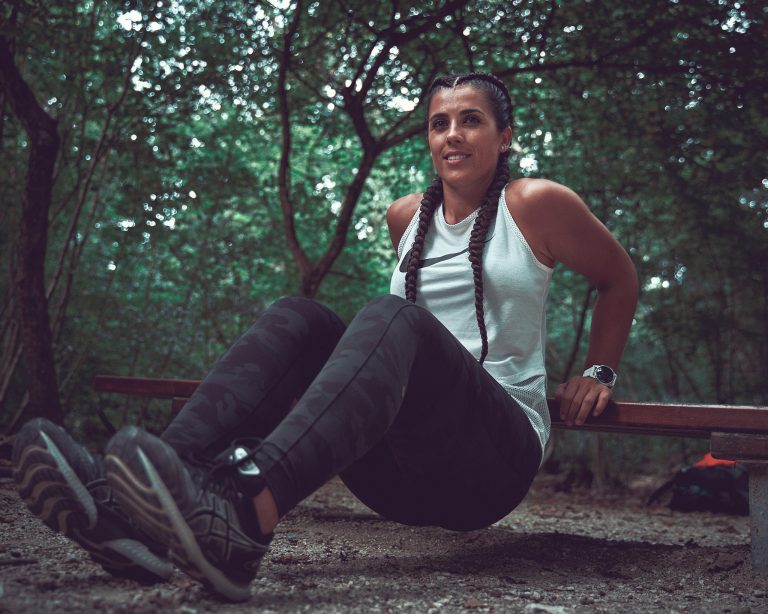 Train with Silvia faisant des triceps sur un banc dans un parc