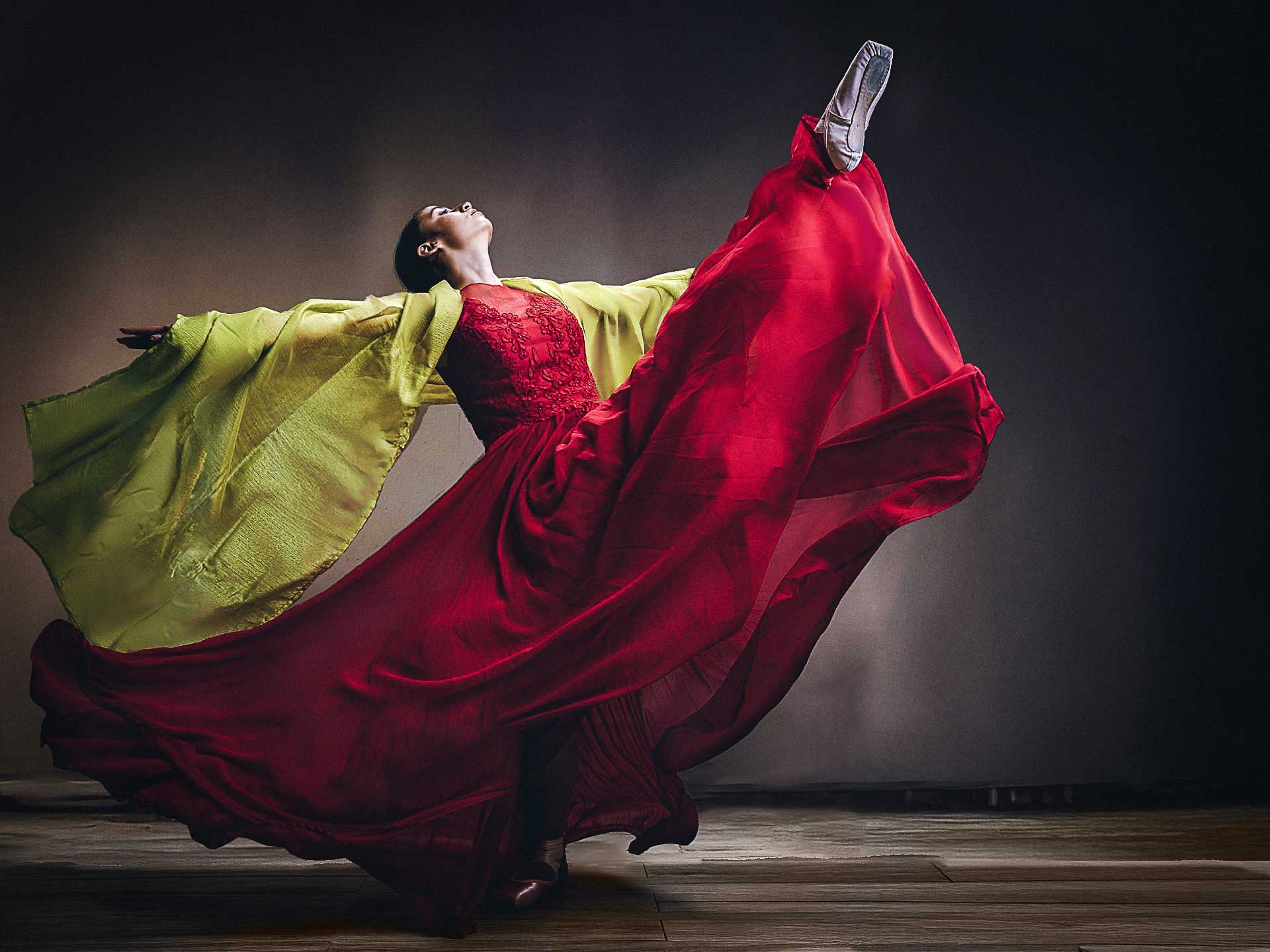 Photo studio d'une ballerine en robe rouge qui contraste avec un tissu vert